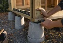 Närbild på snickares händer som fäster träregler på betongfundament under höstlig eftermiddagsljus vid ett påbörjat förråd